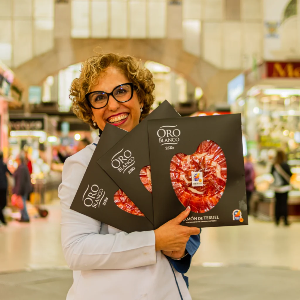 Fotografía para negocios en Valencia con emprendedora mostrando packs de jamón Oro Blanco en el Mercado Central