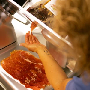 Fotografía para tiendas locales en Valencia mostrando el corte artesanal de jamón mientras se trabaja, sin posar.
