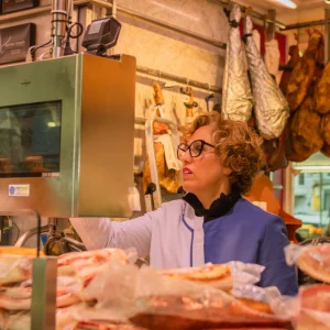 Detalle de pantalla de báscula digital en charcutería, mostrando imagen personalizada de producto gourmet como parte de la experiencia de compra.