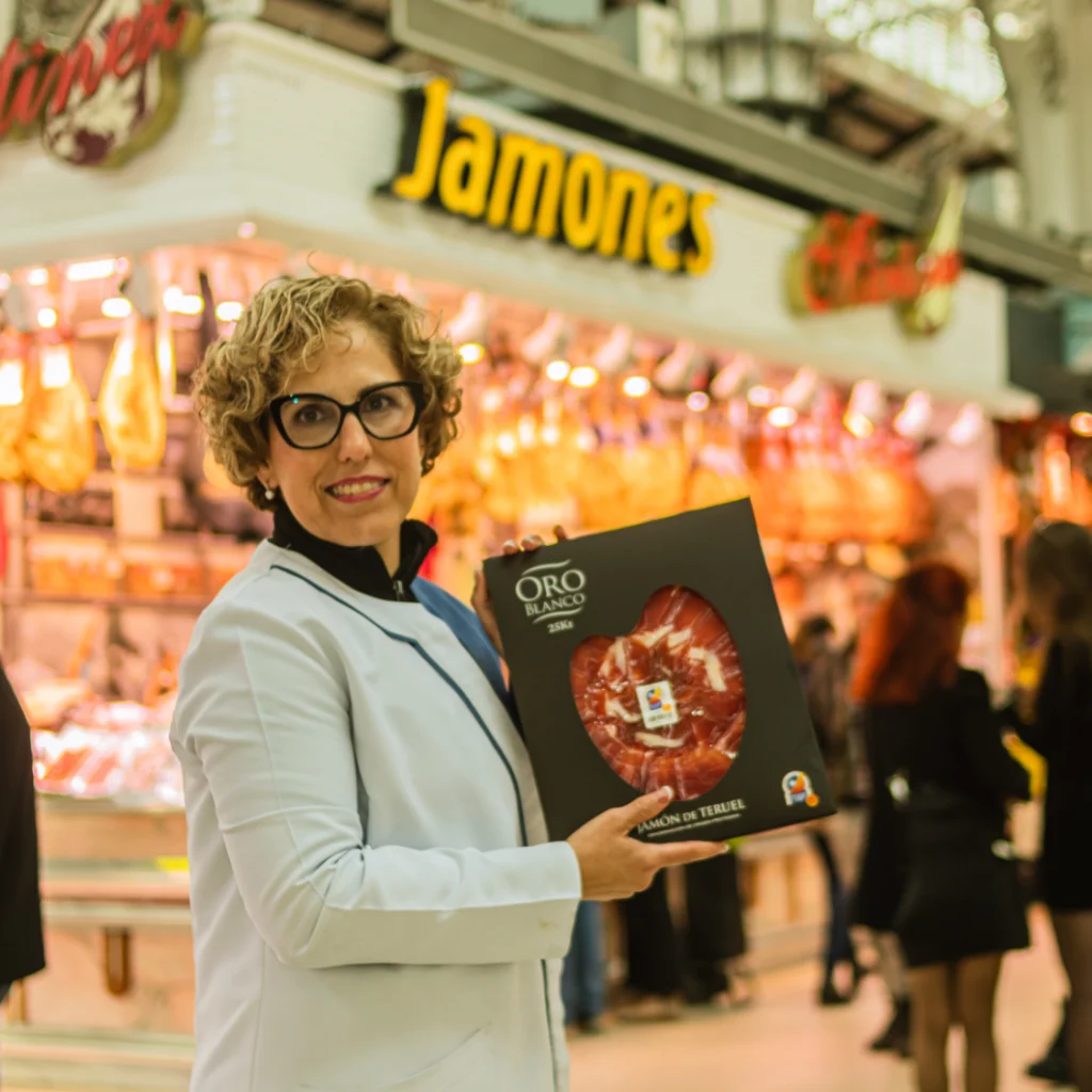 Fotografía para empresas en Valencia con emprendedora mostrando producto local de jamón de Teruel en su tienda
